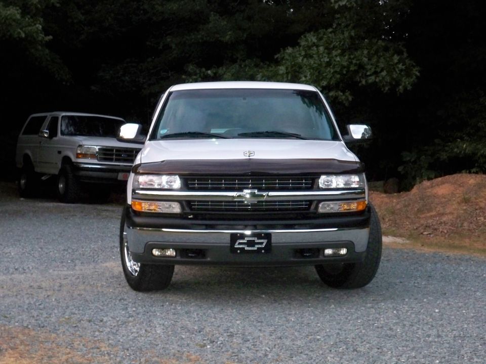 White 2002 Chevrolet Silverado 1500 front view with a Ford Bronco behind it