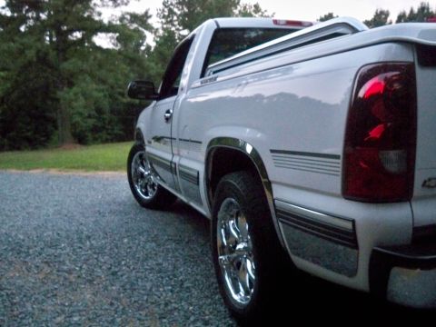 2002 Chevrolet Silverado 1500 - This white pickup truck features chrome wheels and trim, seen from the rear quarter angle.
