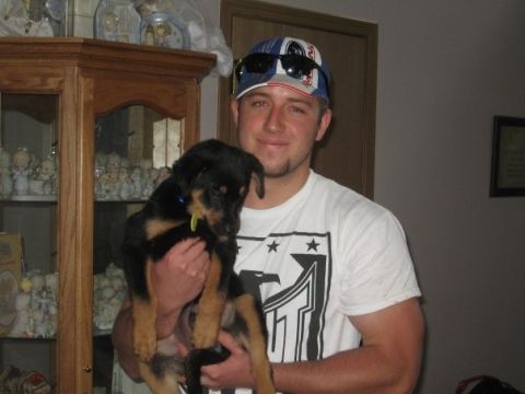 1996 Ford Bronco - Man holds a young rottweiler puppy in front of a display cabinet.