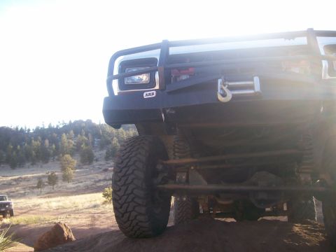 1978 Ford Bronco - Front view of an off-road vehicle with a custom bumper and winch, parked on uneven terrain.