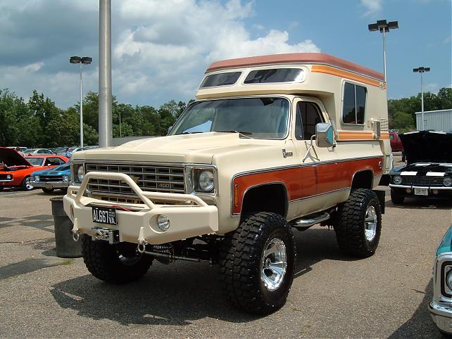 Lifted tan Chevrolet Blazer camper conversion with brush guard and winch at a car show