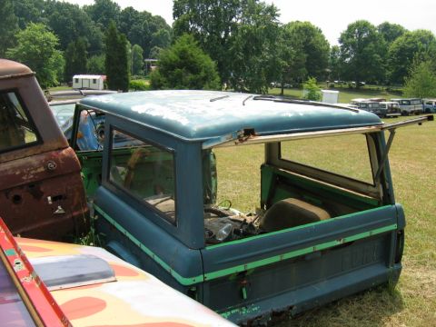 1992 Ford Mustang - This old Ford Bronco is sitting in a junkyard with other vehicles.