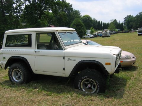 1992 Ford Mustang - A white Ford Bronco sits in a grassy field with other vehicles in the background.