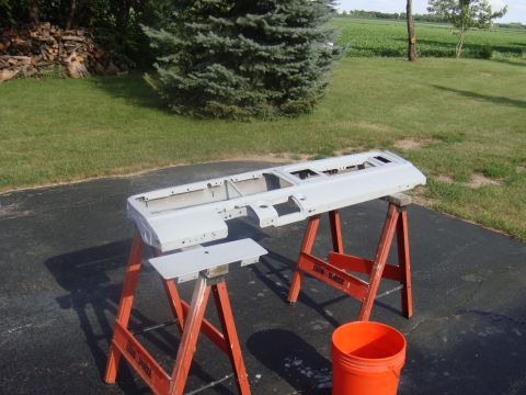 1979 Ford F-250 - A gray truck bed panel is prepped for painting, resting on orange sawhorses outdoors.