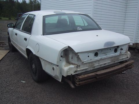 2003 Ford Crown Victoria - A white 2003 Ford Crown Victoria sedan is shown from the rear, missing its bumper and taillights, with a Supermotors.net watermark visible.