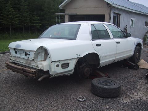 2003 Ford Crown Victoria - This 2003 Ford Crown Victoria is undergoing repairs, with its rear end disassembled and the vehicle supported by jacks.
