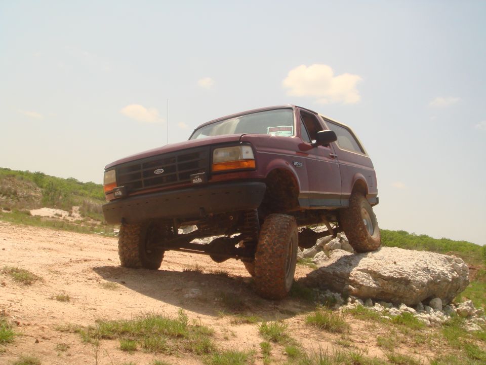 Maroon 1992 Ford Bronco climbing rocks