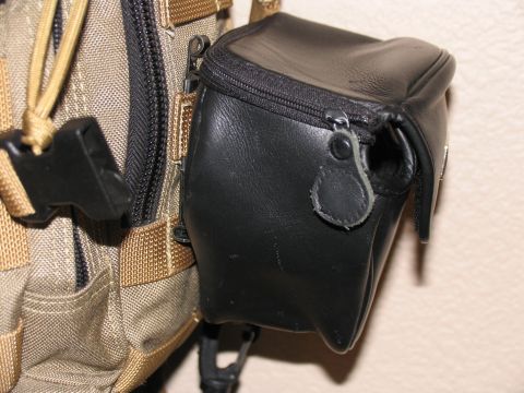 1984 Ford Bronco - A black leather pouch is attached to a tan tactical backpack, showing zippers and straps.