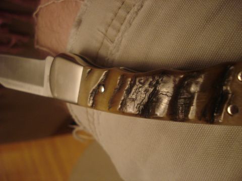2000 Ford Crown Victoria - A folding knife with a polished metal blade and a unique, textured handle is shown.