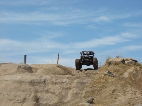 1989 Ford Bronco - A custom off-road buggy navigates a challenging dirt trail on a sunny day.