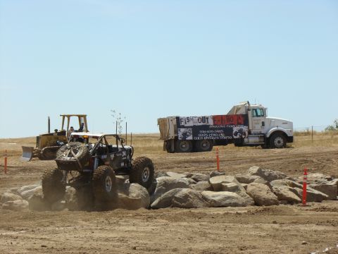 1989 Ford Bronco - A custom off-road buggy tackles a rocky obstacle course, with construction vehicles visible in the distance.