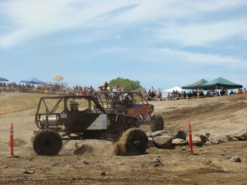 1989 Ford Bronco - Off-road buggies race on a dusty track, kicking up dirt as they navigate the course.