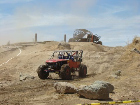 1989 Ford Bronco - Custom off-road vehicles tackle a challenging course on a sunny day.