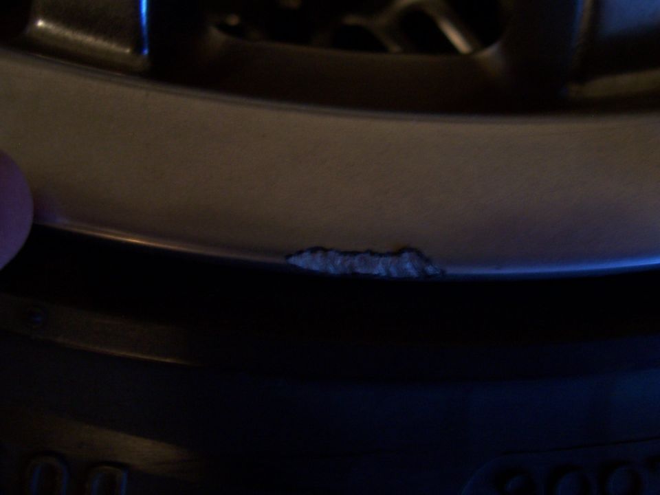 Close-up of a chipped, curved trim edge with a fingertip visible at left in dim light