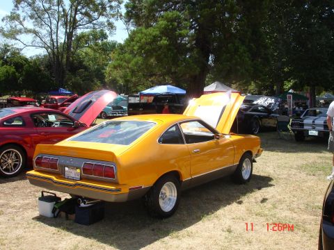 1978 Ford Mustang II - A yellow 1978 Ford Mustang II coupe is displayed with its hood open at an outdoor car show.