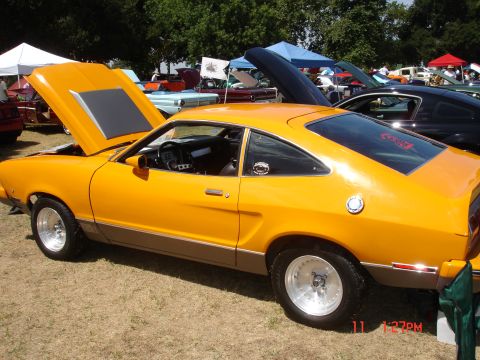 1978 Ford Mustang II - This 1978 Ford Mustang II is displayed at a car show with its hood up, alongside other vehicles.