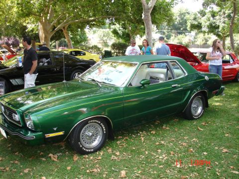 1978 Ford Mustang II - A green coupe with a white interior is displayed at an outdoor car show.
