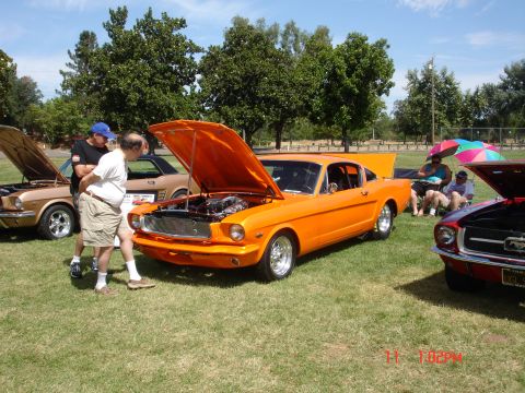 1978 Ford Mustang II - Several classic cars are on display at an outdoor event, with one orange coupe drawing attention.