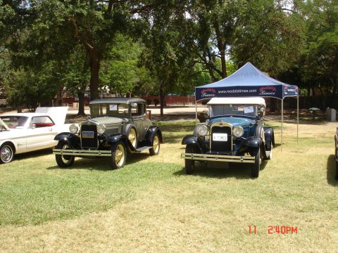 1978 Ford Mustang II - A grey coupe and a blue roadster are displayed at an outdoor car show, with a tent in the background.