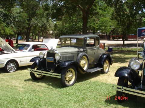 1978 Ford Mustang II - A 1930s Ford coupe is displayed at an outdoor car show next to a 1960s Ford Mustang.