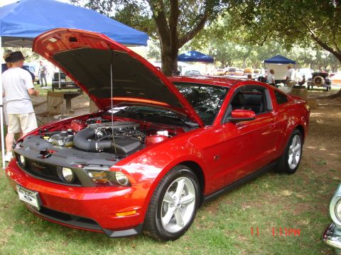 1978 Ford Mustang II - A bright red coupe, possibly a 2010 Ford Mustang, is displayed with its hood open at an outdoor car show.