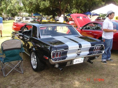 1978 Ford Mustang II - Rear view of a black 1967 Ford Mustang fastback with silver stripes at a car show.