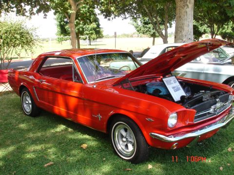 1978 Ford Mustang II - A red coupe is displayed with its hood open, revealing the engine and a descriptive sign.