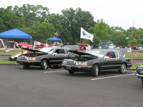 1985 Mercury Cougar - Two classic Mercury Cougars are displayed with their engines exposed at an outdoor event.