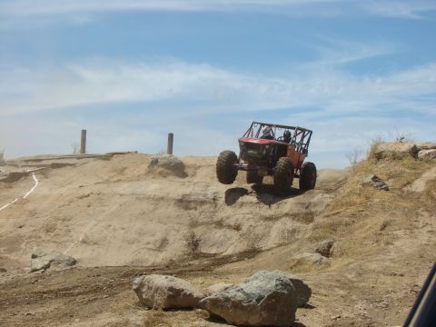 1989 Ford Bronco - This custom buggy is navigating a rocky, off-road course under a partly cloudy sky.