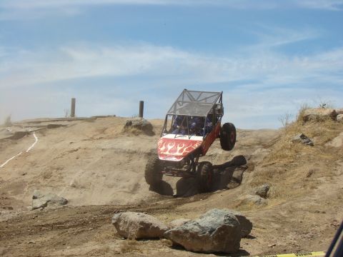 1989 Ford Bronco - A custom-built buggy navigates a challenging off-road course with one wheel lifted.