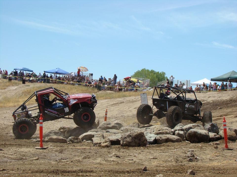 Red off-road buggy with number 18 and black off-road buggy with number 44 navigating rocky terrain