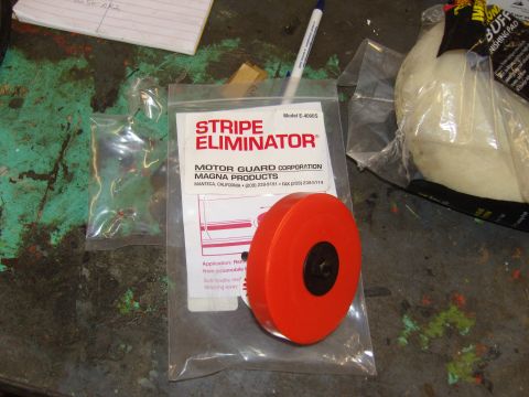 2007 Ford Mustang - A stripe eliminator tool and buffing pad are laid out on a work surface.