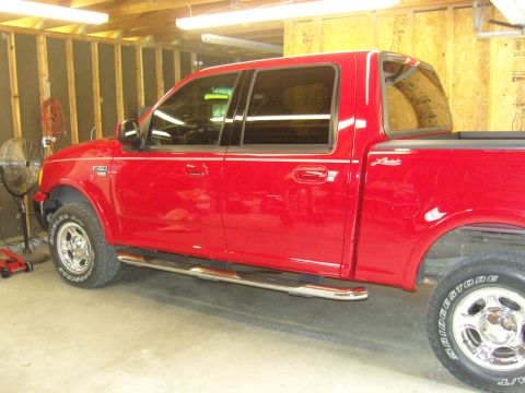 2007 Ford Mustang - Side view of a red pickup truck, identified by the F-150 badge on the fender.