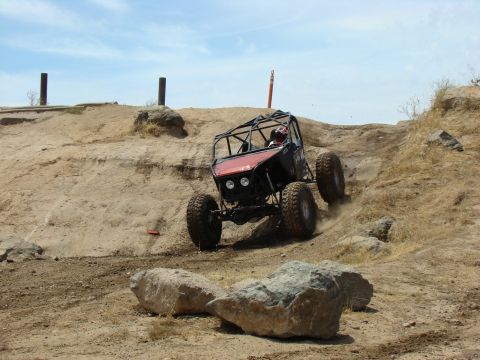 1989 Ford Bronco - Custom off-road buggy navigates a challenging dirt hill climb during an event.