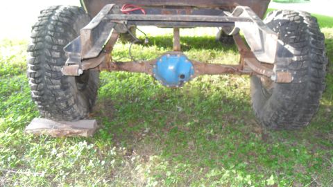 1980 Dodge Magnum - The rear axle and suspension components of a vehicle are visible, with large off-road tires mounted.