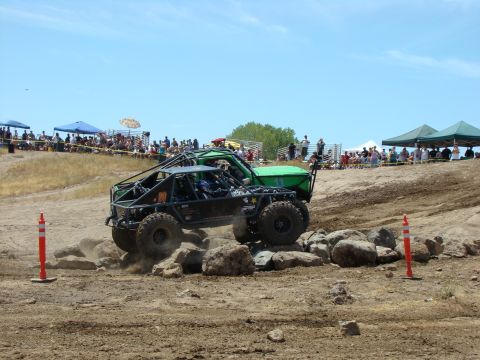 1989 Ford Bronco - Spectators watch as modified off-road vehicles tackle a challenging rock crawling course on a sunny day.