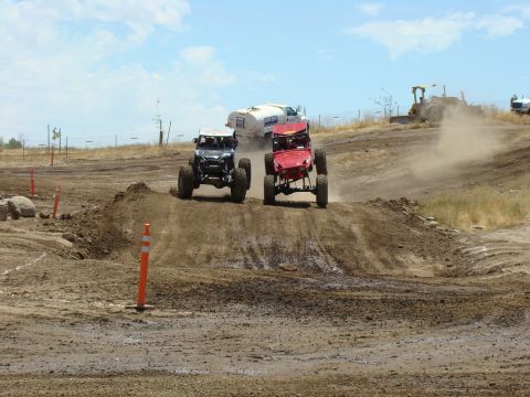 1989 Ford Bronco - Off-road buggies compete on a challenging dirt track under a bright sky.