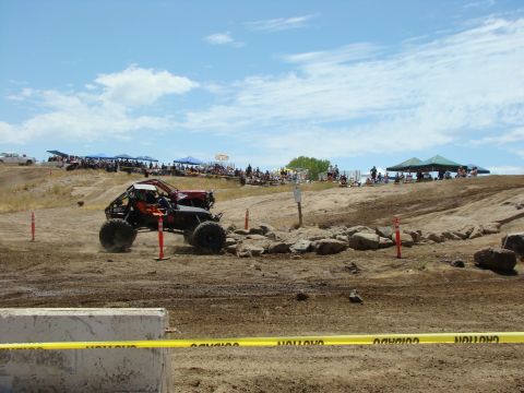 1989 Ford Bronco - A custom off-road buggy navigates a rocky obstacle during a race event with spectators watching.