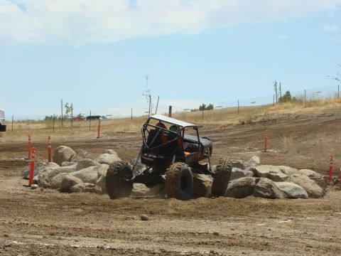 1989 Ford Bronco - A custom off-road buggy with a roll cage maneuvers through a challenging rock garden on a dirt course.