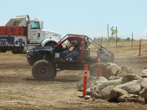1989 Ford Bronco - A custom-built off-road vehicle navigates a challenging course with large rocks and orange cones.