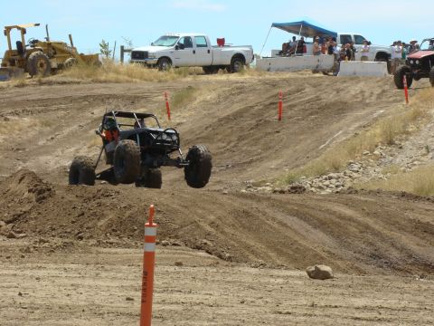 1989 Ford Bronco - A custom off-road buggy jumps over a dirt mound during a race event.