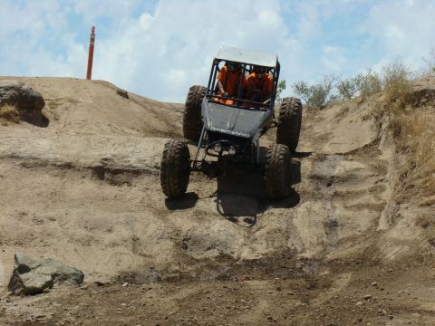 1989 Ford Bronco - A custom off-road buggy navigates a steep, rocky incline on a sunny day.