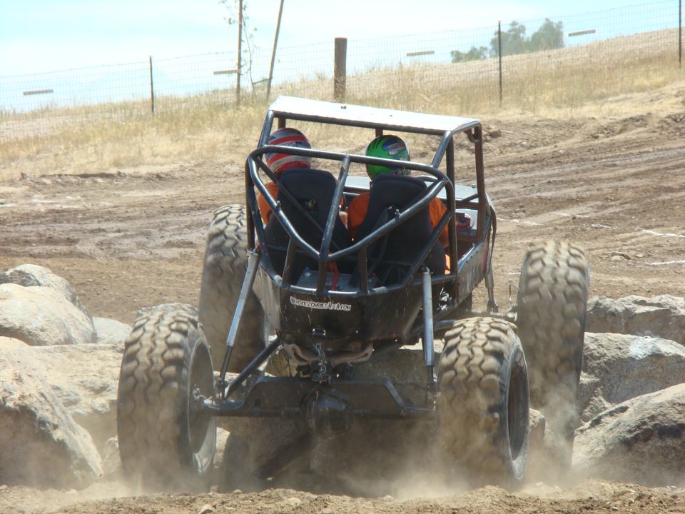 Black off-road buggy with two occupants in helmets navigating rocky terrain