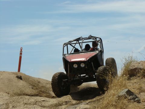 1989 Ford Bronco - This custom-built buggy navigates a challenging off-road course under a bright blue sky.