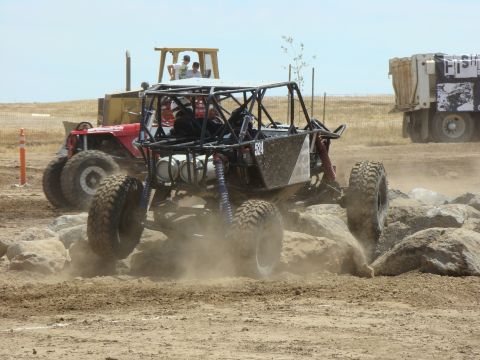 1989 Ford Bronco - A custom-built off-road buggy navigates a rocky course, with a bulldozer and dump truck visible in the distance.