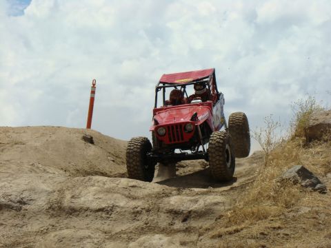 1989 Ford Bronco - Custom off-road buggy navigates a challenging dirt incline during an event.