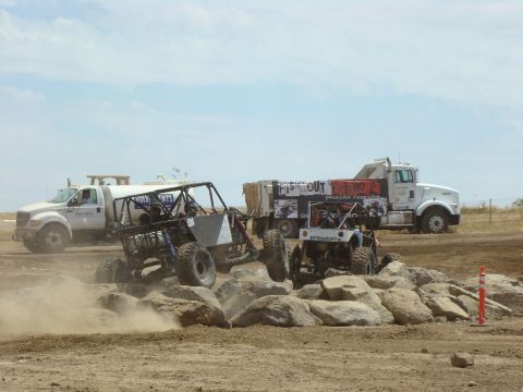 1989 Ford Bronco - Multiple off-road vehicles tackle a challenging rock course under a clear sky.