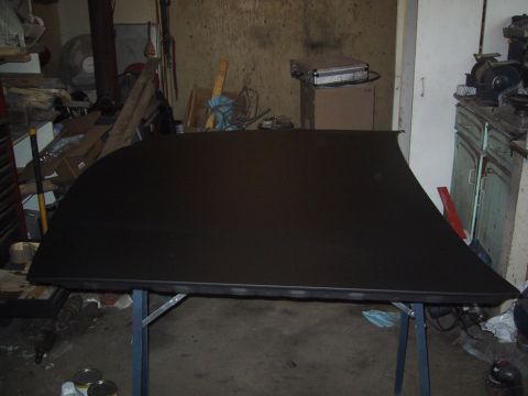 2003 Ford Crown Victoria - A black car roof panel is displayed on a folding table in a cluttered garage setting.