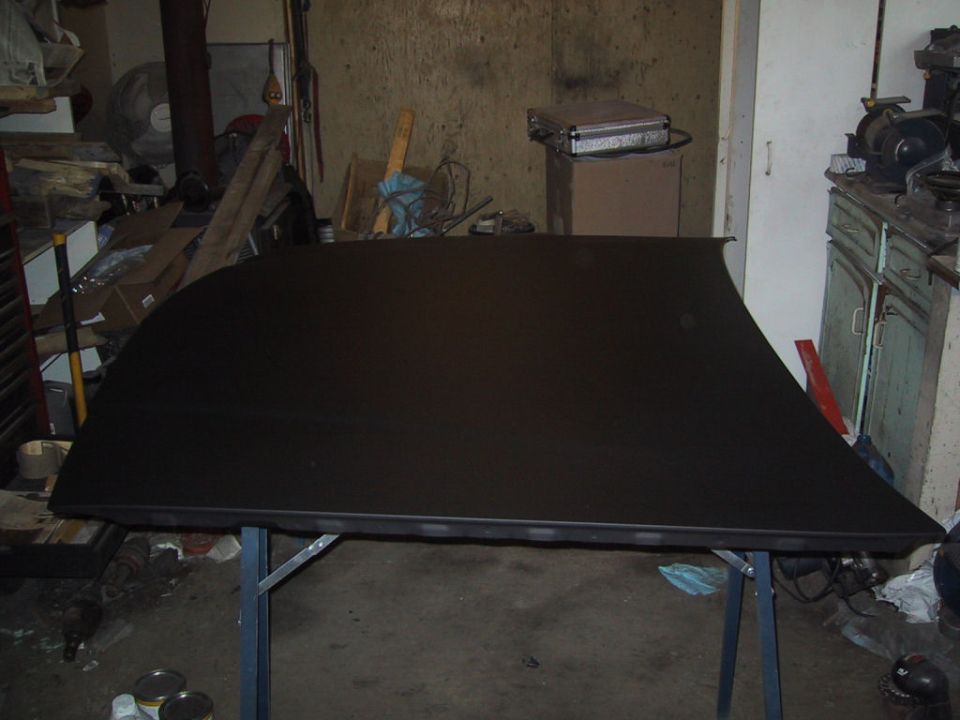 black car roof panel on a table in a garage