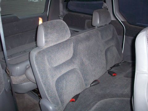 1985 Ford Bronco - Rear interior view of a minivan, showing fabric seats and seatbelt mechanisms.